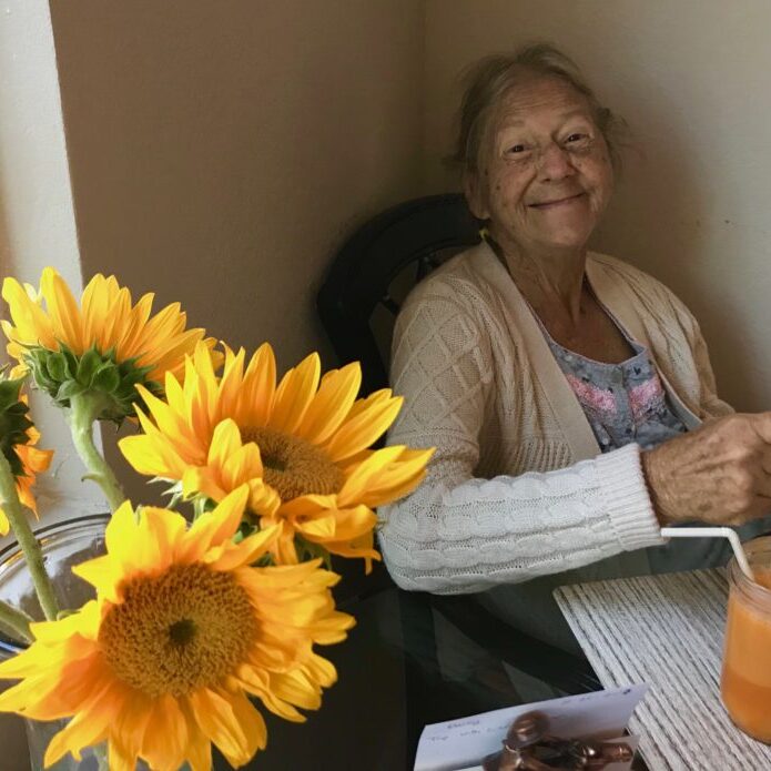 Yellow sunflowers in a vase and Mom smiling brightly